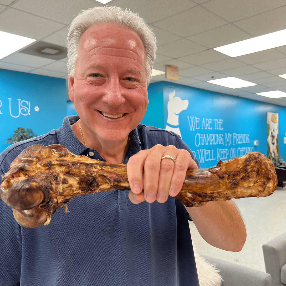 A man holding up a Best Bully Sticks Monster Femur Bone in an office.